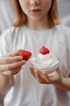 A young girl holds a bowl in her hands and eats strawberries with whipped cream. - PhotoDune Item for Sale