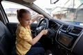 A cute 7-year-old girl is driving a car in the parking lot. - PhotoDune Item for Sale