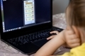 Two sisters 7-8 years old playing a game on a laptop lying on the bed in the room. - PhotoDune Item for Sale