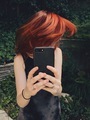 Young woman taking a photo of her newly dyed red hair with her mobile phone  - PhotoDune Item for Sale