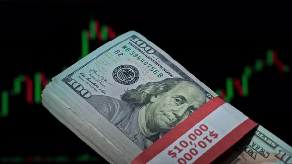 Stack of Dollars in a Hand on the Background of a Stock Market Chart