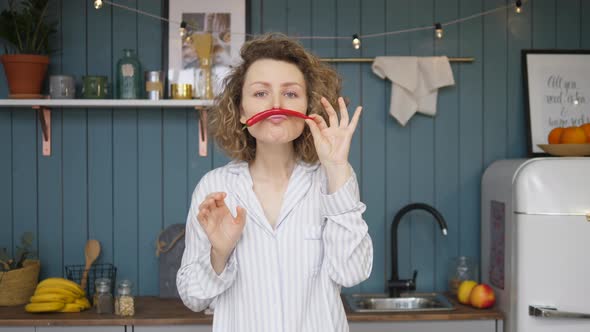 Portrait Of Funny Young Woman With Moustache From Chili Pepper In Kitchen