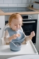 A grubby toddler sitting in a highchair, holding a cookie and eating. A baby feeding himself. - PhotoDune Item for Sale
