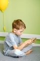An engrossed in game preschool boy looking tensely uses a mobile. A kid watches a video on cellphone - PhotoDune Item for Sale