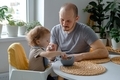 A father and child. A young dad supporting his baby toddler self-feeding. Family lunchtime.  - PhotoDune Item for Sale