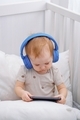 A cute toddler watching cartoons using a cellphone and Bluetooth headphones. Kids and technology.  - PhotoDune Item for Sale