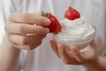 A young girl holds a bowl in her hands and eats strawberries with whipped cream. - PhotoDune Item for Sale