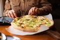 Woman eating a delicious pizza with seafood closeup on the table at cafe or pizzeria or restaurant.  - PhotoDune Item for Sale