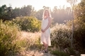 Young pregnant woman standing in a natural setting holding her baby belly - PhotoDune Item for Sale