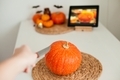 pumpkin on the table, making jack o lantern by carving orange pumpkin while watching online tutorial - PhotoDune Item for Sale