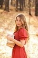 Beautiful woman in red orange dress with long hair in autumn park holding books - PhotoDune Item for Sale