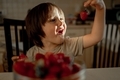 the boy happily looks at the strawberries. A child eats a berry - PhotoDune Item for Sale