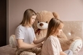 Two sisters are sitting on the bed in the room and the older sister is combing the younger one's hai - PhotoDune Item for Sale