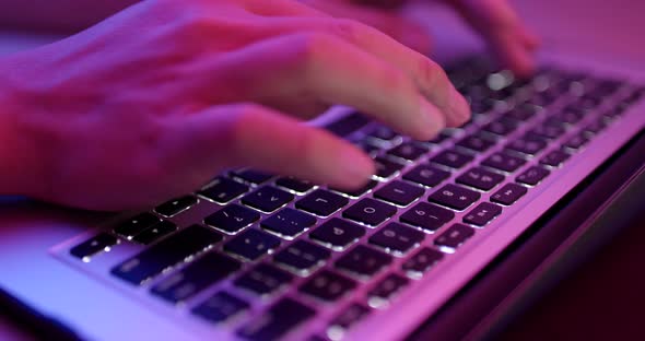 Typing on notebook computer keyboard with pink light