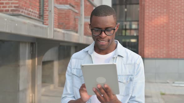 African Man Working on Tablet While Walking in Street