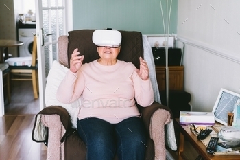 Senior woman wearing virtual reality goggles at home. Emotional lady with virtual headset