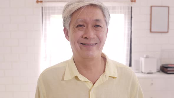 Asian elderly man feeling happy smiling and looking to camera while relax on the sofa.