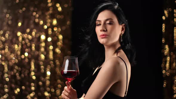 Portrait of Fashion Woman with Glass of Red Wine Posing at Disco Party