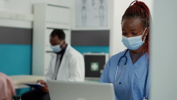 Portrait of African American Nurse with Face Mask Working on Laptop