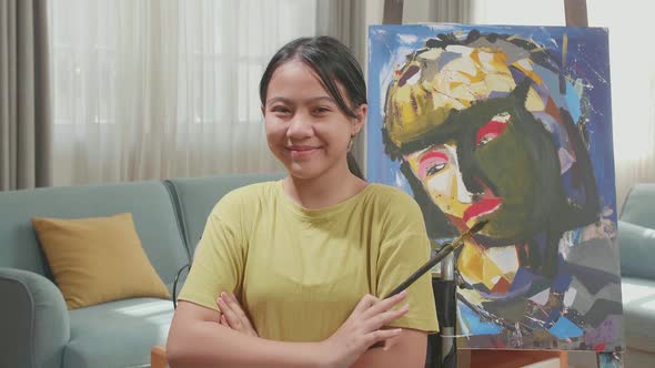 Asian Artist Girl In Wheelchair Holding Paintbrush And Cross His Arms And Smile While Painting