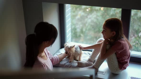 Asian mom and daughter stroking their dog