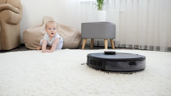 Robot Vacuum Cleaner Moving Toward Little Baby Boy Crawling on Floor at House