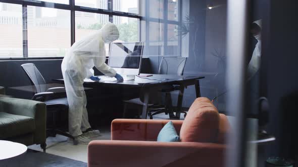 Cleaners wearing protective clothes sanitizing modern office space