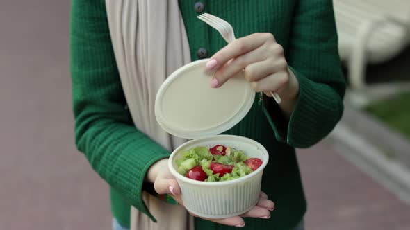 Hands of Woman Opening Bowl with Vegetables Salad for Lunch