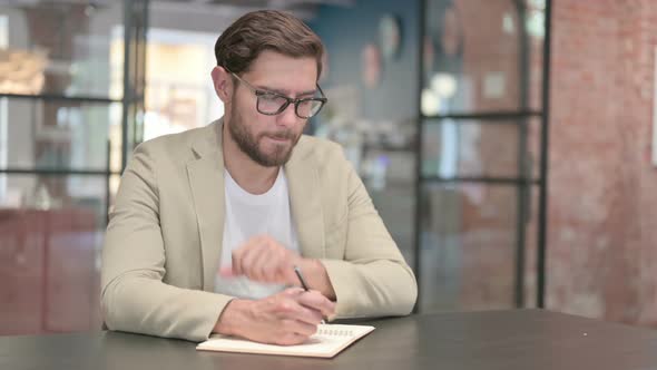 Pensive Young Man Writing on Paper Thinking