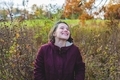 Beautiful millennial smiling, laughing woman wearing a purple jacket in an autumnal field of nature - PhotoDune Item for Sale