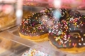 Chocolate donuts at a bakery behind glass with rainbow sprinkles - PhotoDune Item for Sale