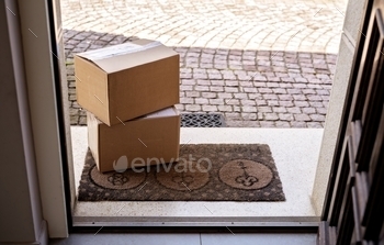 o carton boxes delivered and left outside at entrance door. View from inside through open door. contactless; delivery; quarantine; pandemic; self isolation; social distancing; service; post; box; carton; parcel; delivered; entrance; outdoors; door; stairs; open; house; receiving; order; internet; shopping; online; coronavirus; left; nobody; no contact; porch; yard; shipment; postal; package; home; food; doorstep; courier; cardboard; buying