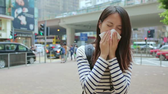 Woman sneezing at outdoor in Hong Kong city 