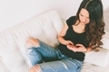 A young woman sitting on the couch with her smartphone.  - PhotoDune Item for Sale