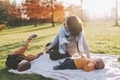 A grandmother playing with her grandchildren in the park at sunset.  - PhotoDune Item for Sale