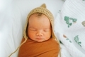 A swaddled newborn baby sleeping in a bonnet.  - PhotoDune Item for Sale