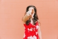 Young woman on a simple orange wall pointing a finger at the camera.  - PhotoDune Item for Sale