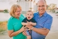 Happy, smiling Grandparents holding their grand child at the beach on a sunny day.  - PhotoDune Item for Sale