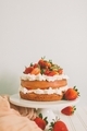 A strawberry layer cake with whipped cream and fresh berries against a simple background.  - PhotoDune Item for Sale
