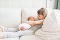 A boy holding his newborn baby brother on the couch.  - PhotoDune Item for Sale