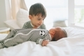 An older brother looking lovingly at his new baby brother in a bright white bedroom.  - PhotoDune Item for Sale