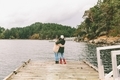 Two women friends hugging at the end of a dock, looking out at the view.  - PhotoDune Item for Sale