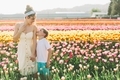 A mother and her little boy holding hands and standing together in a field of tulips in spring.  - PhotoDune Item for Sale