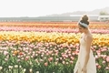 A woman in a yellow sun dress walking through a field of tulips in Spring.  - PhotoDune Item for Sale