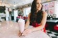 A beautiful young woman with a strawberry milkshake sitting at a counter in a retro diner.  - PhotoDune Item for Sale