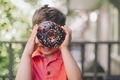 A little boy looking through the centre of a chocolate donut with sprinkles.  - PhotoDune Item for Sale