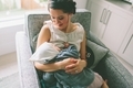 A mother nursing her baby girl at home in a comfy chair.  - PhotoDune Item for Sale