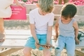 Two little boys looking at a phone while sitting on a bench.  - PhotoDune Item for Sale