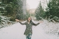 A happy woman throwing snow into the air in a forest on a winter day.  - PhotoDune Item for Sale