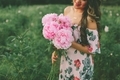A woman in a dress holding a beautiful bouquet of pink peonies in a field.  - PhotoDune Item for Sale
